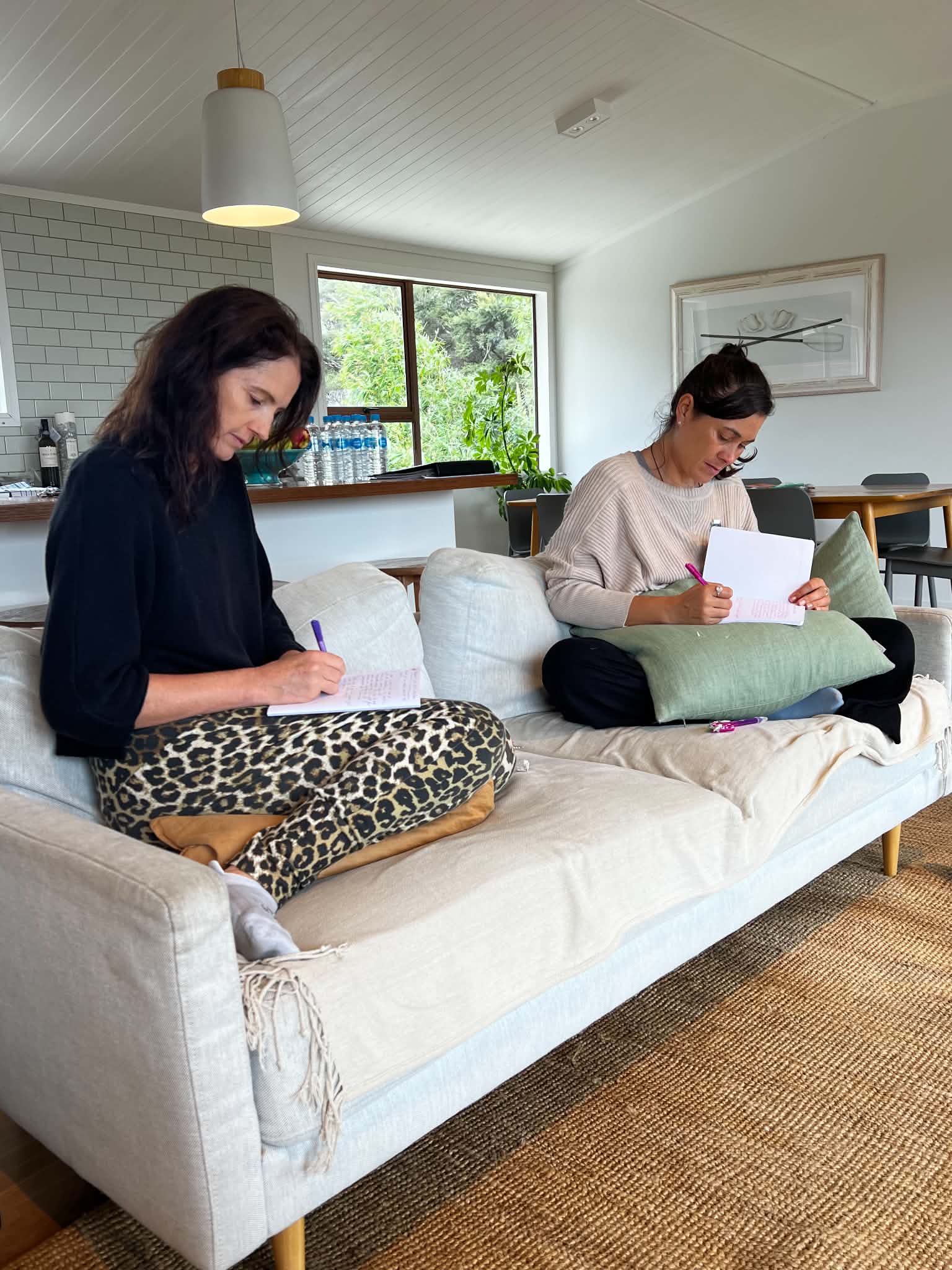 Two writers deep in their manuscripts on the couch during a Createcation retreat