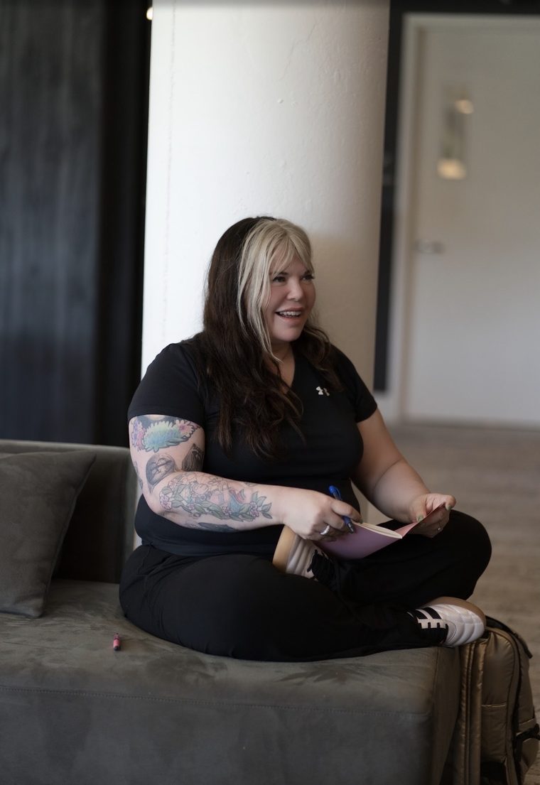 A writer cross-legged with a notebook, mid-laugh